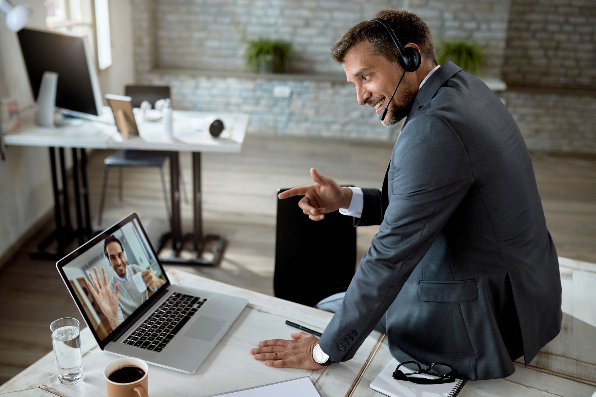 A smart man is sitting at the desk and talking in an online meeting with a client